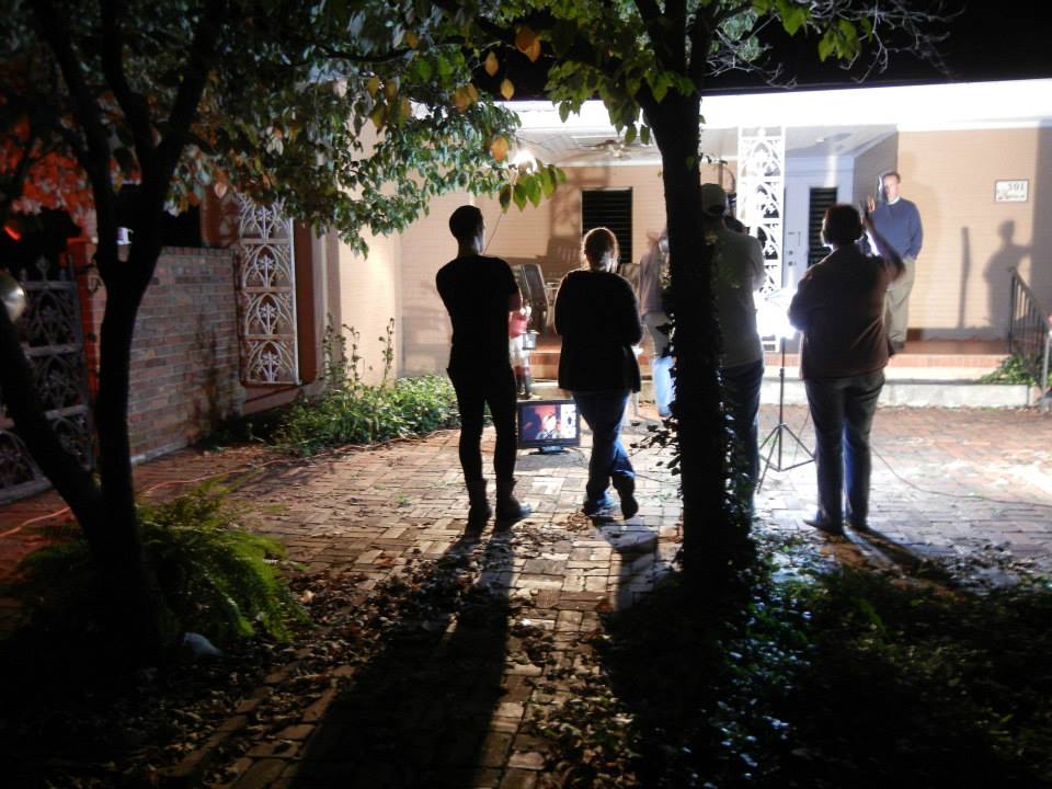 Four film crew members facing the outdoor set.